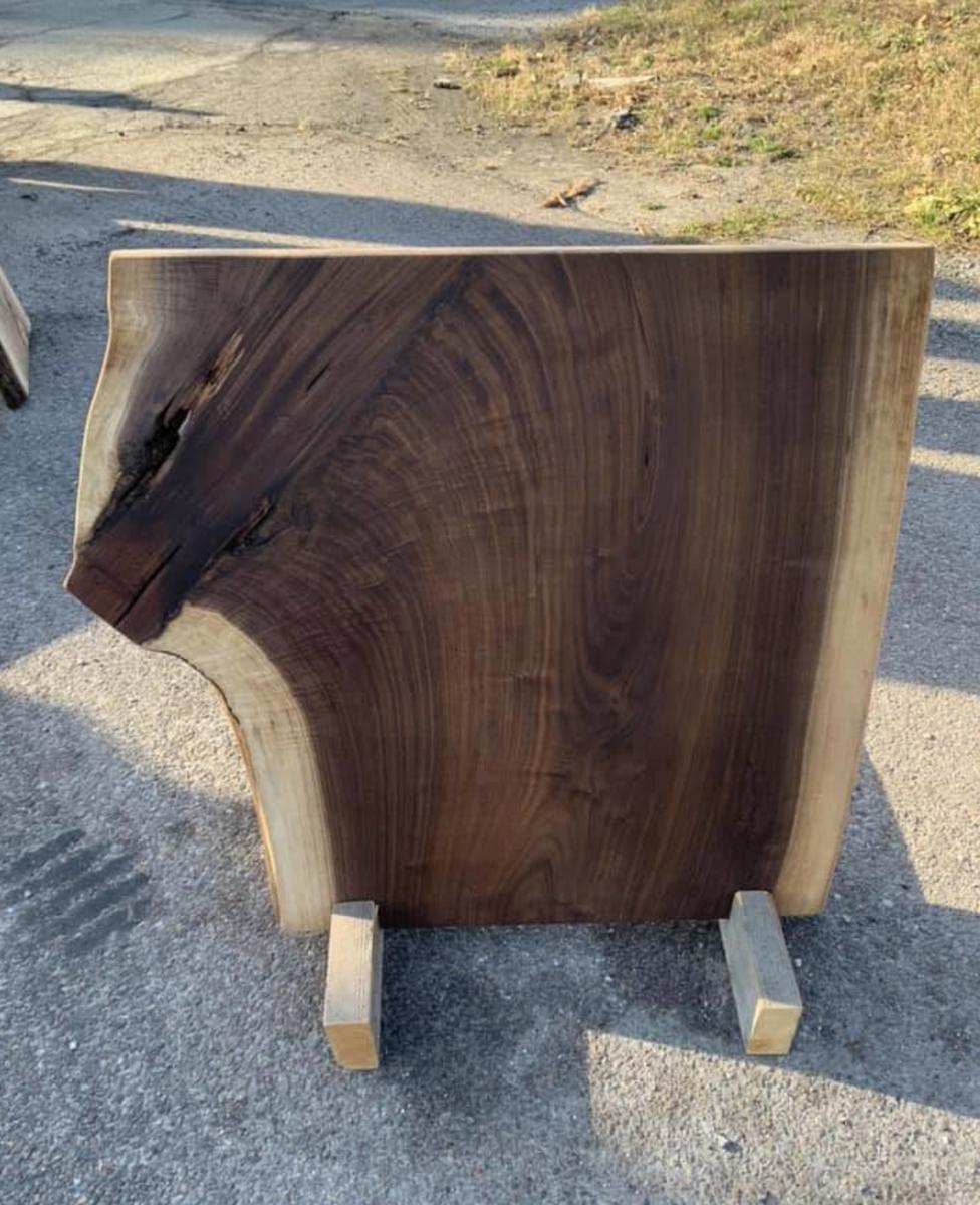 Dark live edge slab displayed on a stand